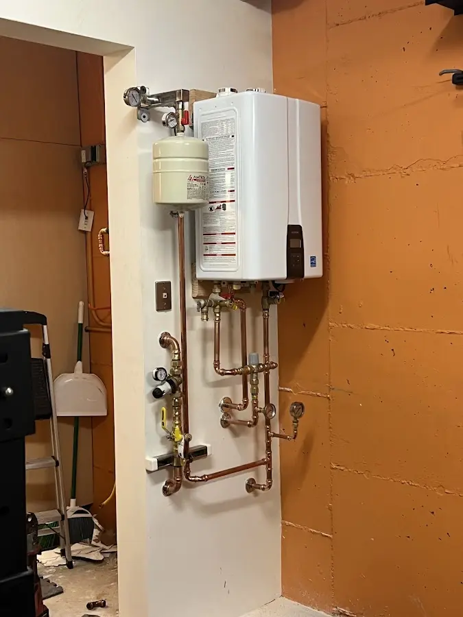 Plumbing technician inspecting water heater connections in Irondequoit